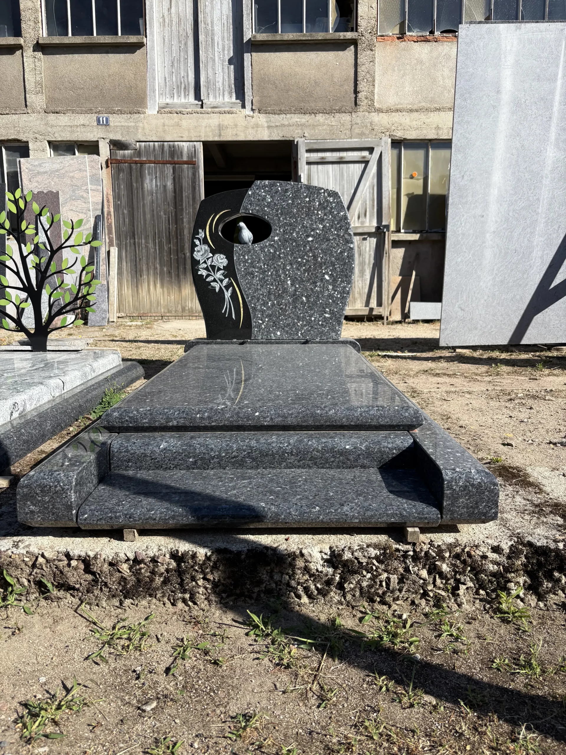 Pierre tombale sur mesure en granit sombre poli gravée d'une colombe et de roses
