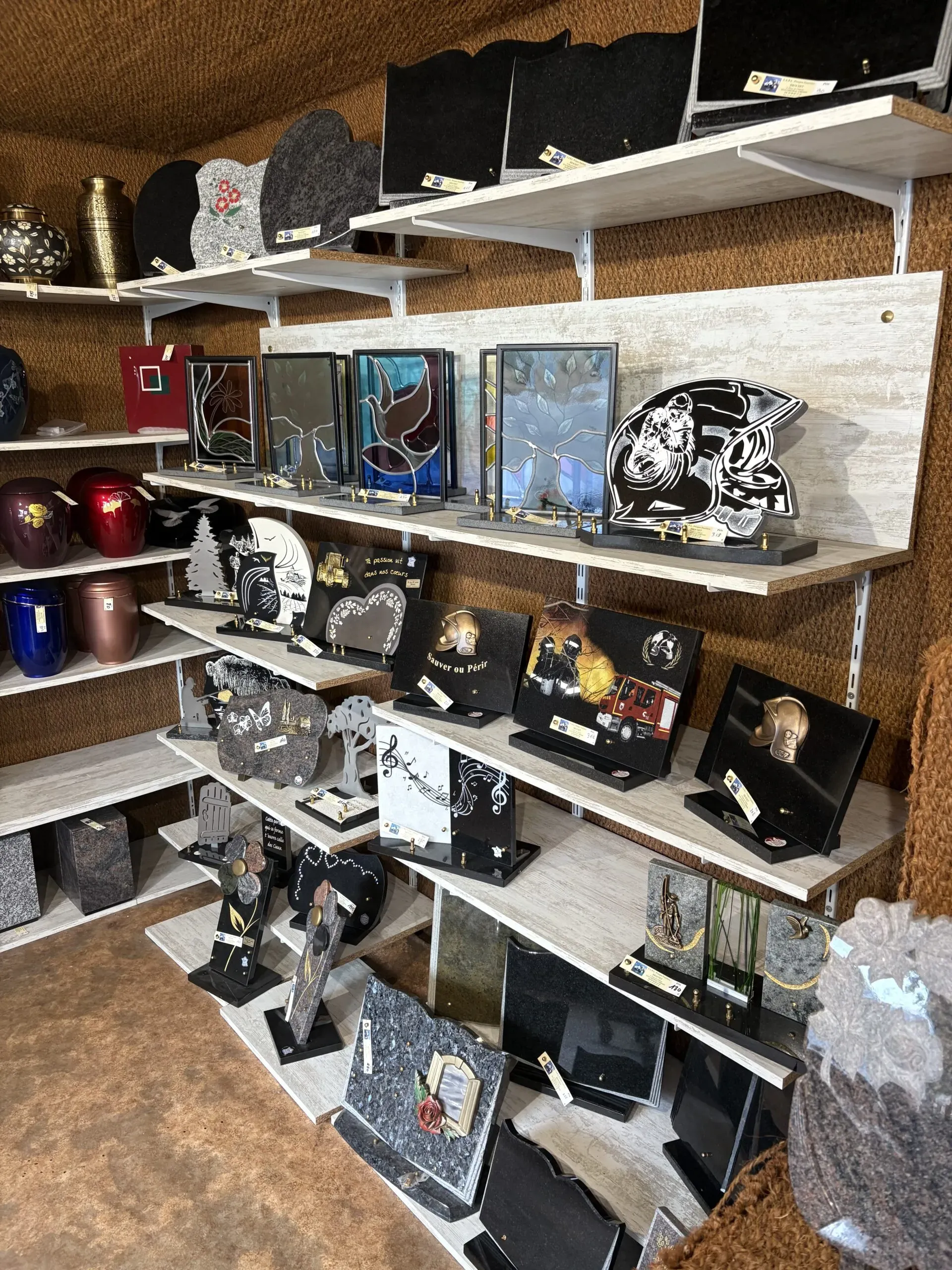Rayonnages en bois présentant une collection de plaques funéraires gravées.