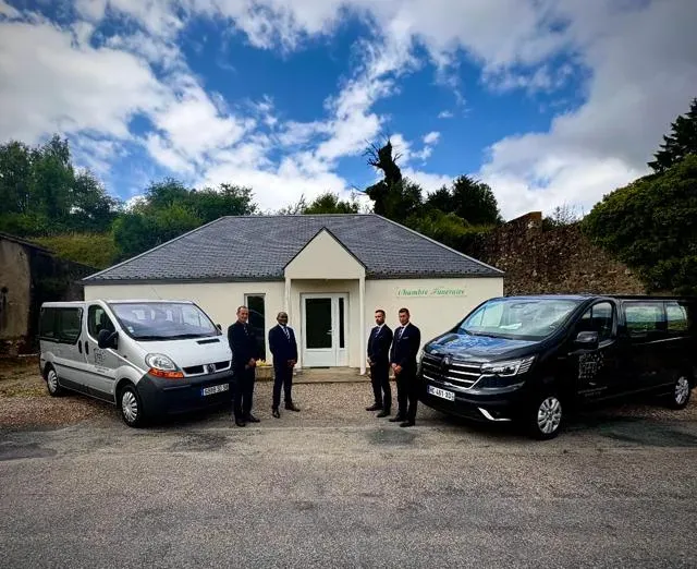 Agents funéraires et véhicules de transport devant la façade d'une chambre funéraire